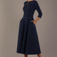 Model wearing the Perpetua A-line dress in navy blue with hands in pockets (Navy Blue)