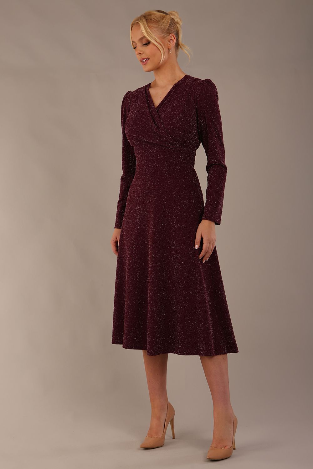 Model wearing the Calvert sparkle A-line dress in burgundy, showing the wrap V-neckline highlighting the fluid A-line skirt and long sleeves (Burgundy Sparkle)