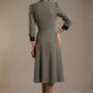 Woman wearing a diva catwalk Alanna Dogtooth Tie-Detail A-Line Dress | Diva Catwalk with long sleeves against a plain background back view (Petite Dogtooth Check)