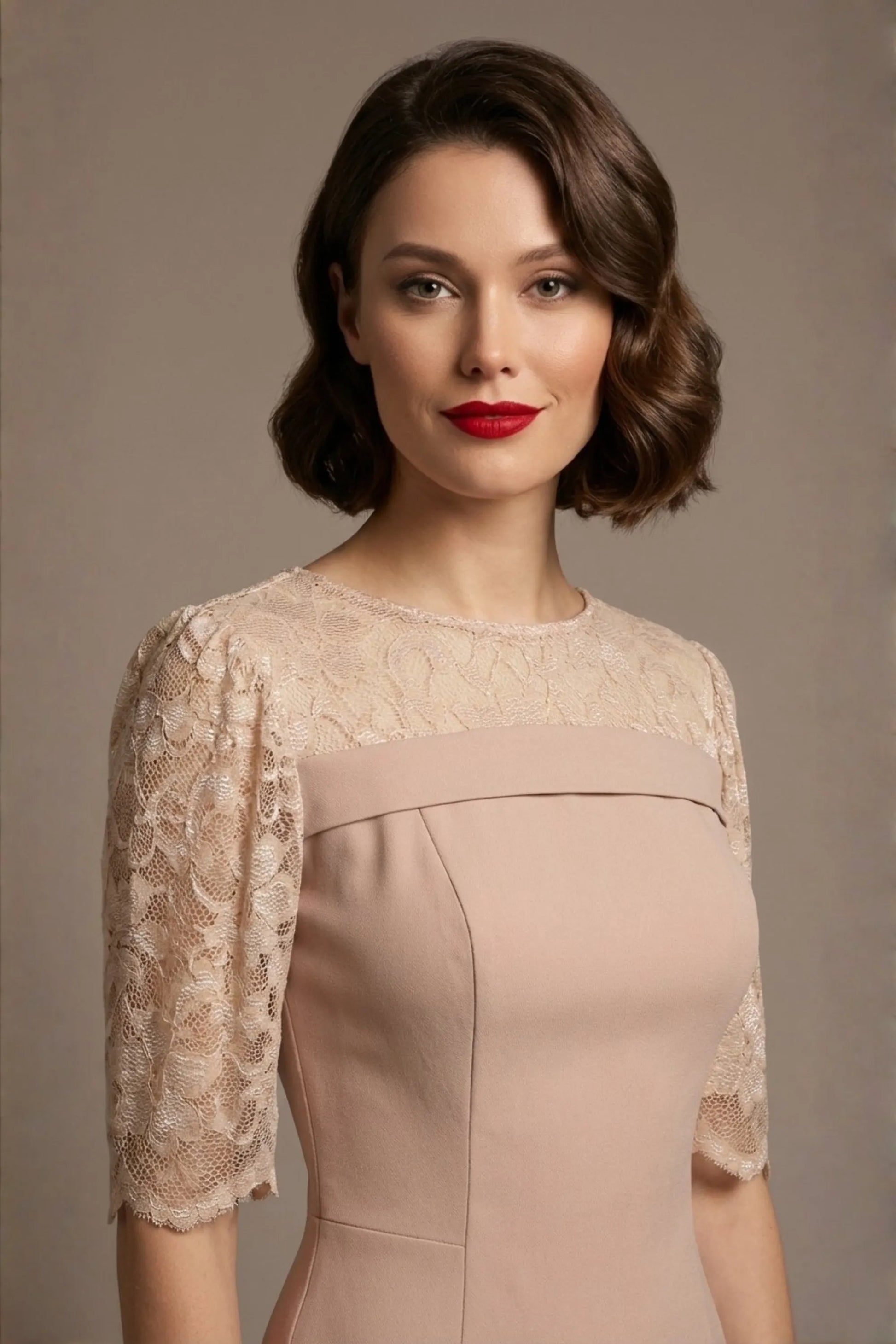 Woman wearing a diva catwalk Francesca Lace Fluted Dress in pink haze colour dress with lace sleeves against a brown background front close up (Pink Haze)