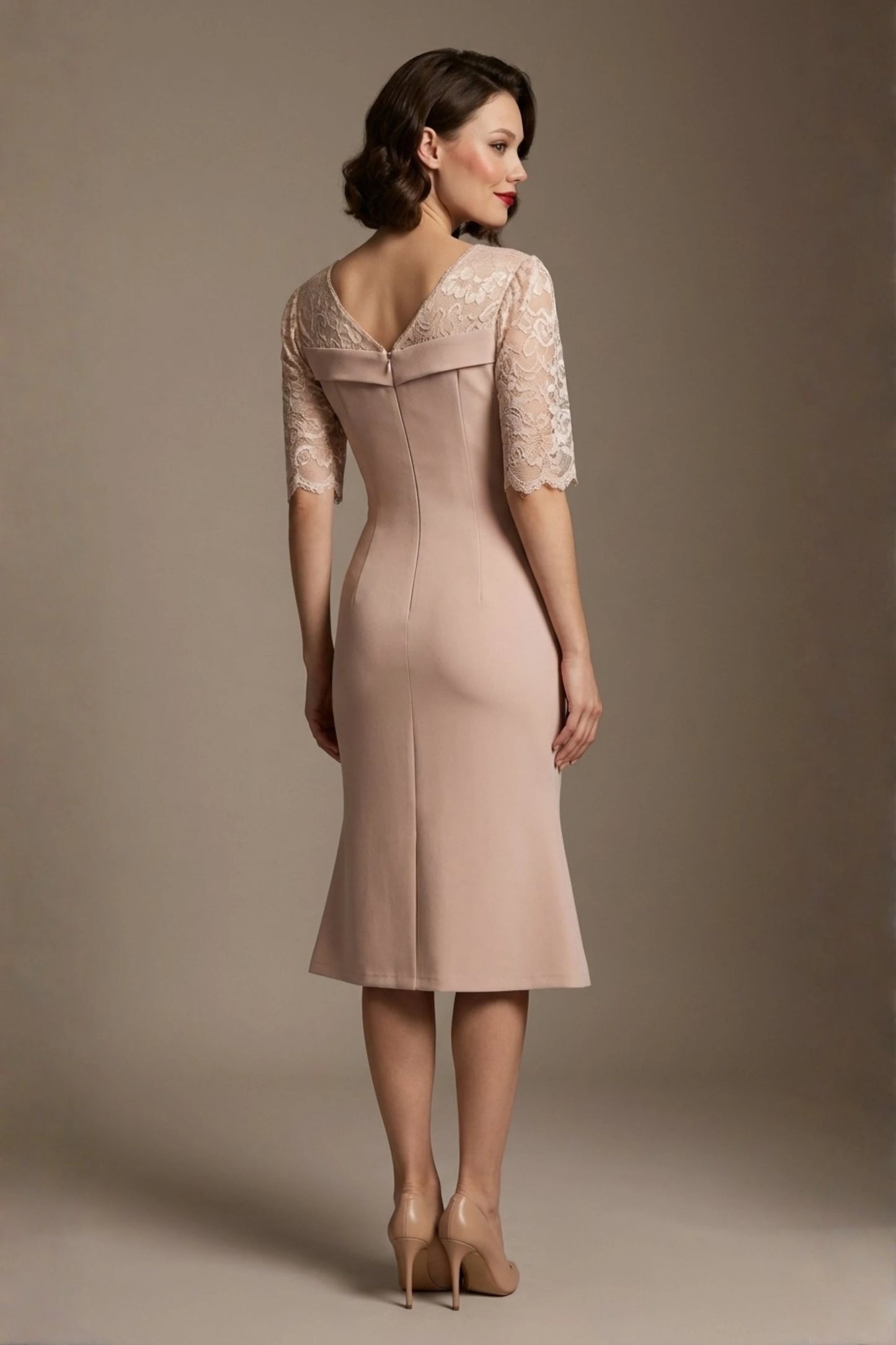Woman wearing a diva catwalk Francesca Lace Fluted Dress in pink haze colour dress with lace sleeves against a brown background back view (Pink Haze)