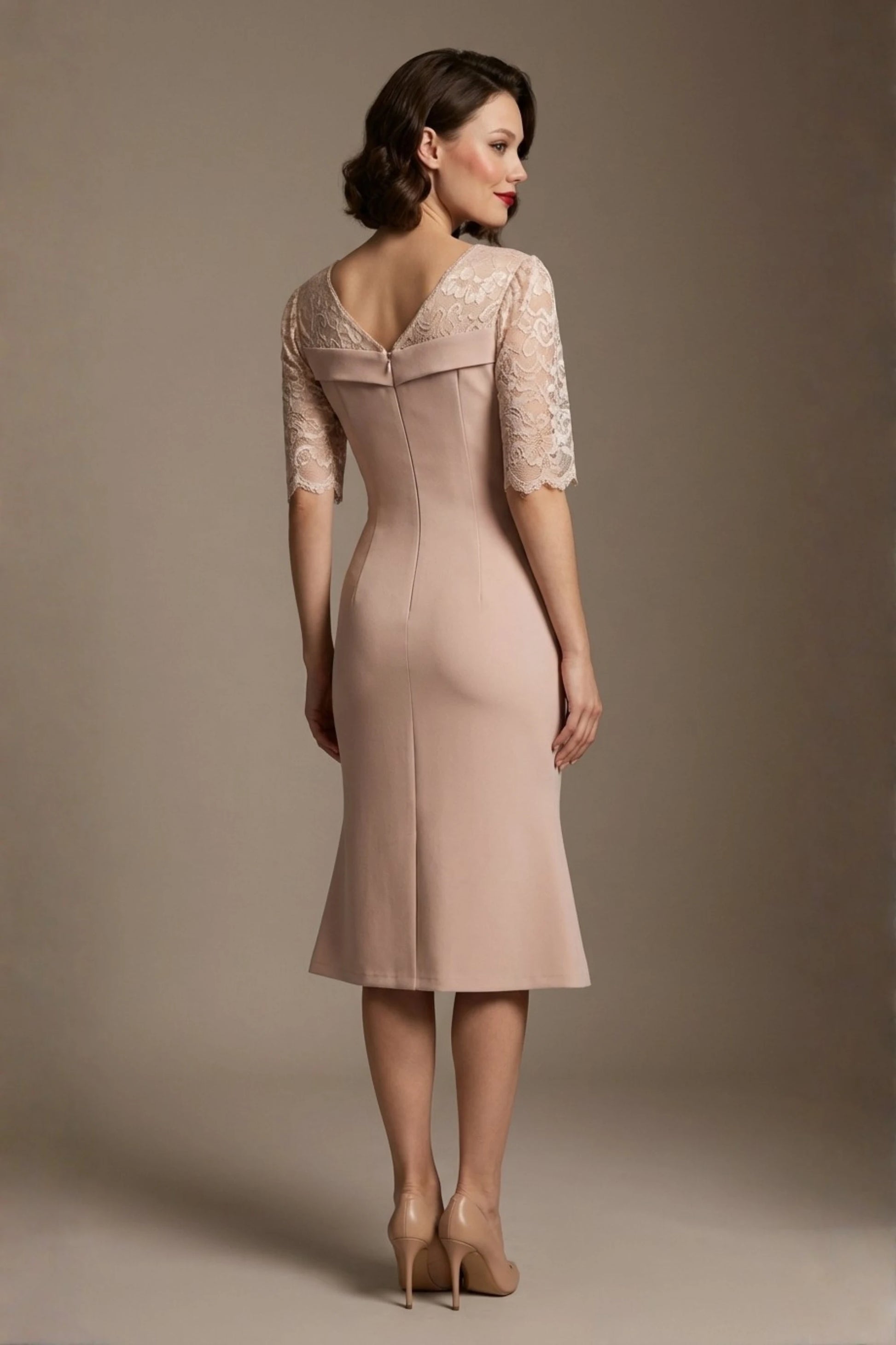 Woman wearing a diva catwalk Francesca Lace Fluted Dress in pink haze colour dress with lace sleeves against a brown background back view (Pink Haze)