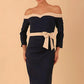 Model wearing a diva catwalk Brittany Off Shoulder Bow detail Pencil Dress with 3/4 sleeves and knee length in Navy Blue and Sandshell Beige colour front side