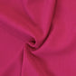 A close-up of draped bright pink fabric with soft folds and a subtle woven texture.