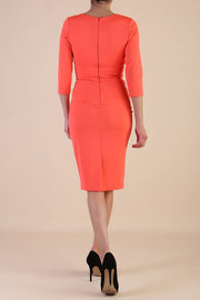 Model wearing Diva catwalk Daphne ¾ Sleeved pencil-skirt dress with pleat detail across the hips and ¾ sleeve length in hot coral front
