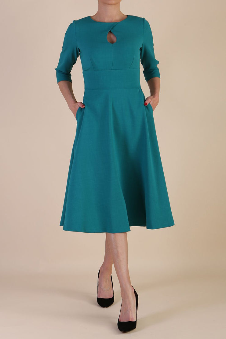 Brunette model is wearing diva catwalk casares swing dress with a keyhole neckline three quarter sleeve dress with pocket detail in parasailing green front