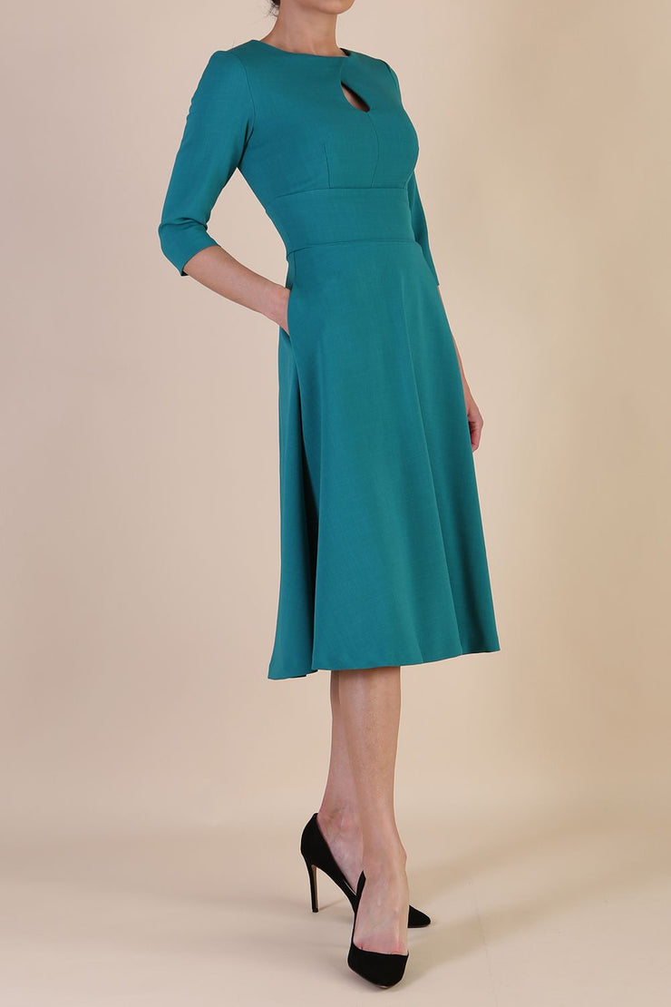 Brunette model is wearing diva catwalk casares swing dress with a keyhole neckline three quarter sleeve dress with pocket detail in parasailing green side front