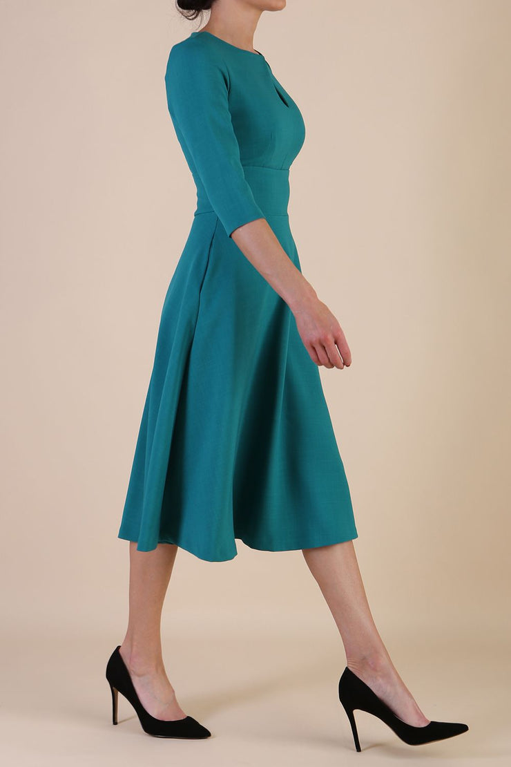 Brunette model is wearing diva catwalk casares swing dress with a keyhole neckline three quarter sleeve dress with pocket detail in parasailing green front side