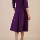 Brunette model is wearing diva catwalk casares swing dress with a keyhole neckline three quarter sleeve dress with pocket detail in imperial purple back
