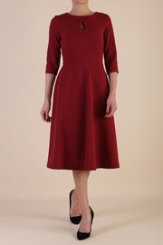 Brunette model is wearing diva catwalk casares swing dress with a keyhole neckline three quarter sleeve dress with pocket detail in wine front
