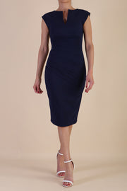 brunette model wearing diva catwalk lydia sleeveless pencil flattering fitted plain dress with split neckline and pleating across the body navy blue front