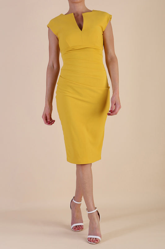 brunette model wearing diva catwalk lydia sleeveless pencil flattering fitted plain dress with split neckline and pleating across the body Mustard Yellow front