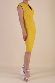 brunette model wearing diva catwalk lydia sleeveless pencil flattering fitted plain dress with split neckline and pleating across the body Mustard Yellow front