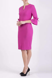 blonde model wearing diva catwalk zoe 3 4 sleeve formal dress with a split rounded neckline and split on skirt in pink colour front