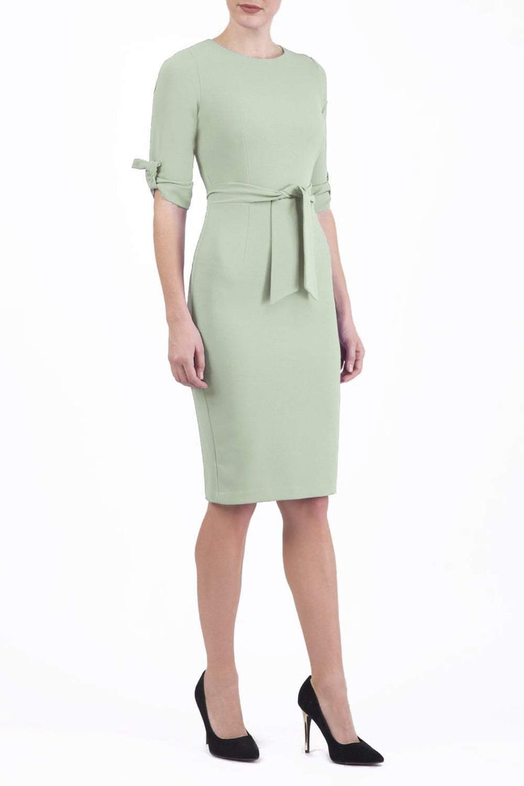 brunette model wearing diva catwalk tryst pencil deco green dress with sleeves and belt detail at the front with rounded neckline front
