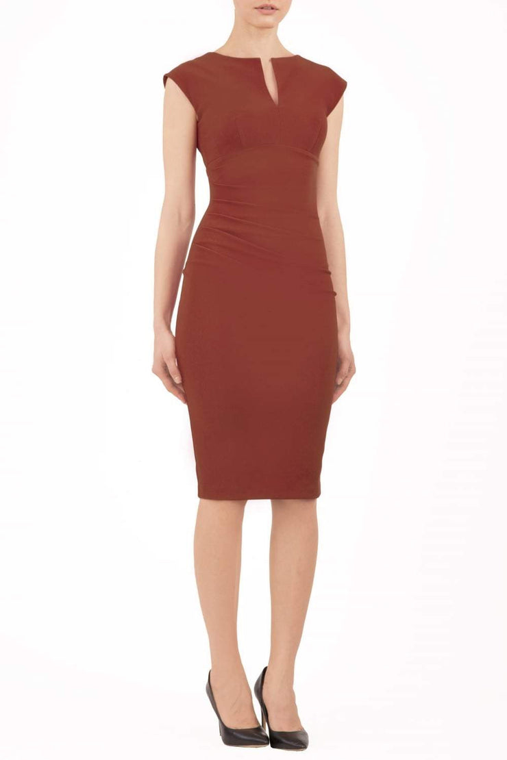 brunette model wearing diva catwalk lydia sleeveless pencil flattering fitted plain dress with split neckline and pleating across the body terracotta brown front