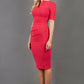 blonde model is wearing diva catwalk lydia short sleeve pencil fitted dress in paradise pink colour with rounded neckline with a slit in the middle front