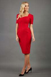 blonde model wearing seed belgravia square neckline red pencil dress with short pleated sleeves and folded pleating at the front