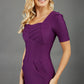 blonde model wearing seed belgravia square neckline purple pencil dress with short pleated sleeves and folded pleating at the front
