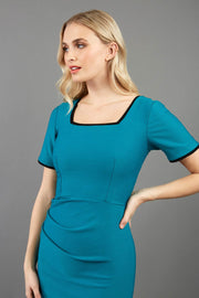 blonde model wearing seed albany contrasted pencil-skirt dress with short sleeves and pleating across the tummy with low square neckline and contrasted detail finishing in teal front