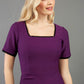 blonde model wearing seed albany contrasted pencil-skirt dress with short sleeves and pleating across the tummy with low square neckline and contrasted detail finishing in purple front