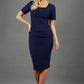 blonde model wearing seed albany contrasted pencil-skirt dress with short sleeves and pleating across the tummy with low square neckline and contrasted detail finishing in navy blue front