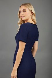 blonde model wearing seed albany contrasted pencil-skirt dress with short sleeves and pleating across the tummy with low square neckline and contrasted detail finishing in navy blue back