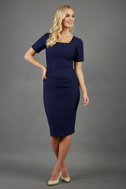 blonde model wearing seed albany contrasted pencil-skirt dress with short sleeves and pleating across the tummy with low square neckline and contrasted detail finishing in navy blue front