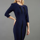 blonde model wearing seed lace navy dress with sleeves and rounded necline with lace details pointing towards the band