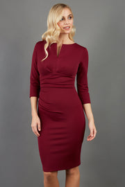 model wearing diva catwalk donna pencil dress in burgundy colour with wide band and sleeves and rounded neckline with low split in front