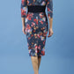 model is wearing diva catwalk stamford pencil dress with low v-neck and wide contrasting band in circle hidcote floral back