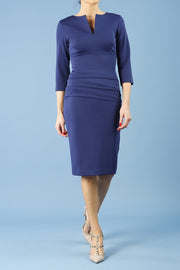 Model wearing the Diva Daphne ¾ Sleeved dress with pleat detail across the hips and ¾ sleeve length in navy front
