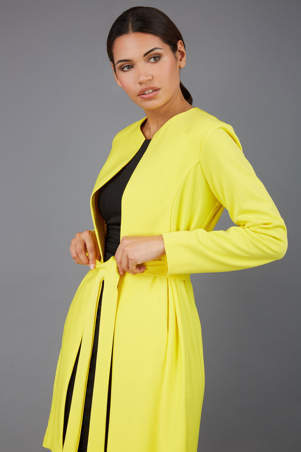 model wearing diva catwalk yellow coat with long sleeves and a belt front