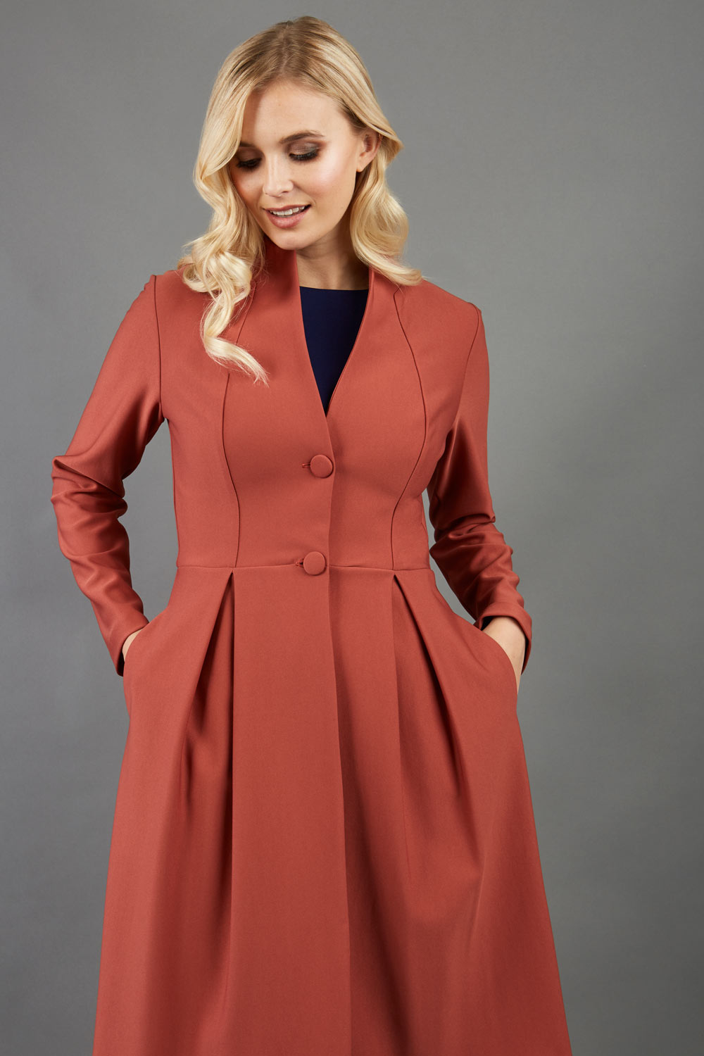 Blonde hair model wearing long sleeve bi stretch Taylor coat in Marsala Brown front image