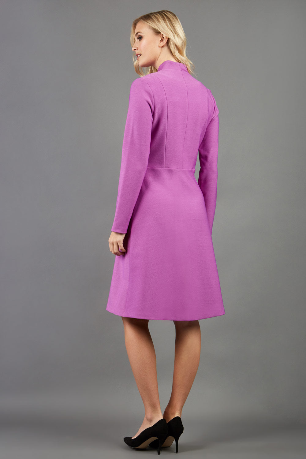 blonde model wearing diva catwalk couture fine raquella coat with buttons across the front and long sleeves with high neck and pockets in magenta mist colour back image