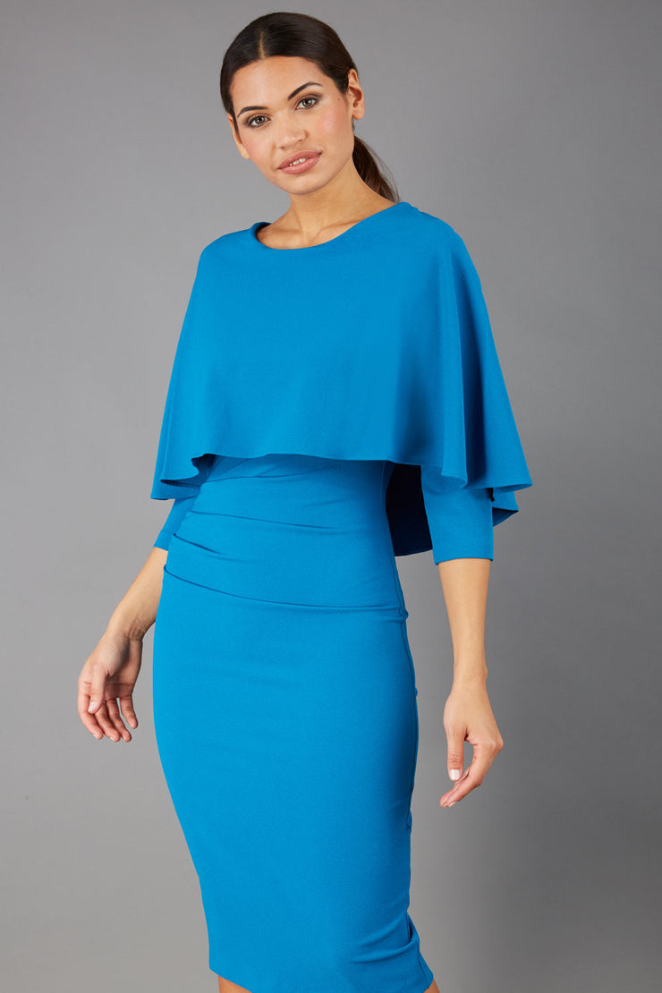 model wearing diva catwalk lizanne pencil-skirt dress with an attached wide cape detail and 3 4 sleeves in colour tropical teal front
