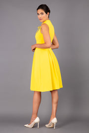 brunette model wearing diva catwalk oceana a-line swing skirt sleeveless dress with funnel neckline and tie detail in yellow back