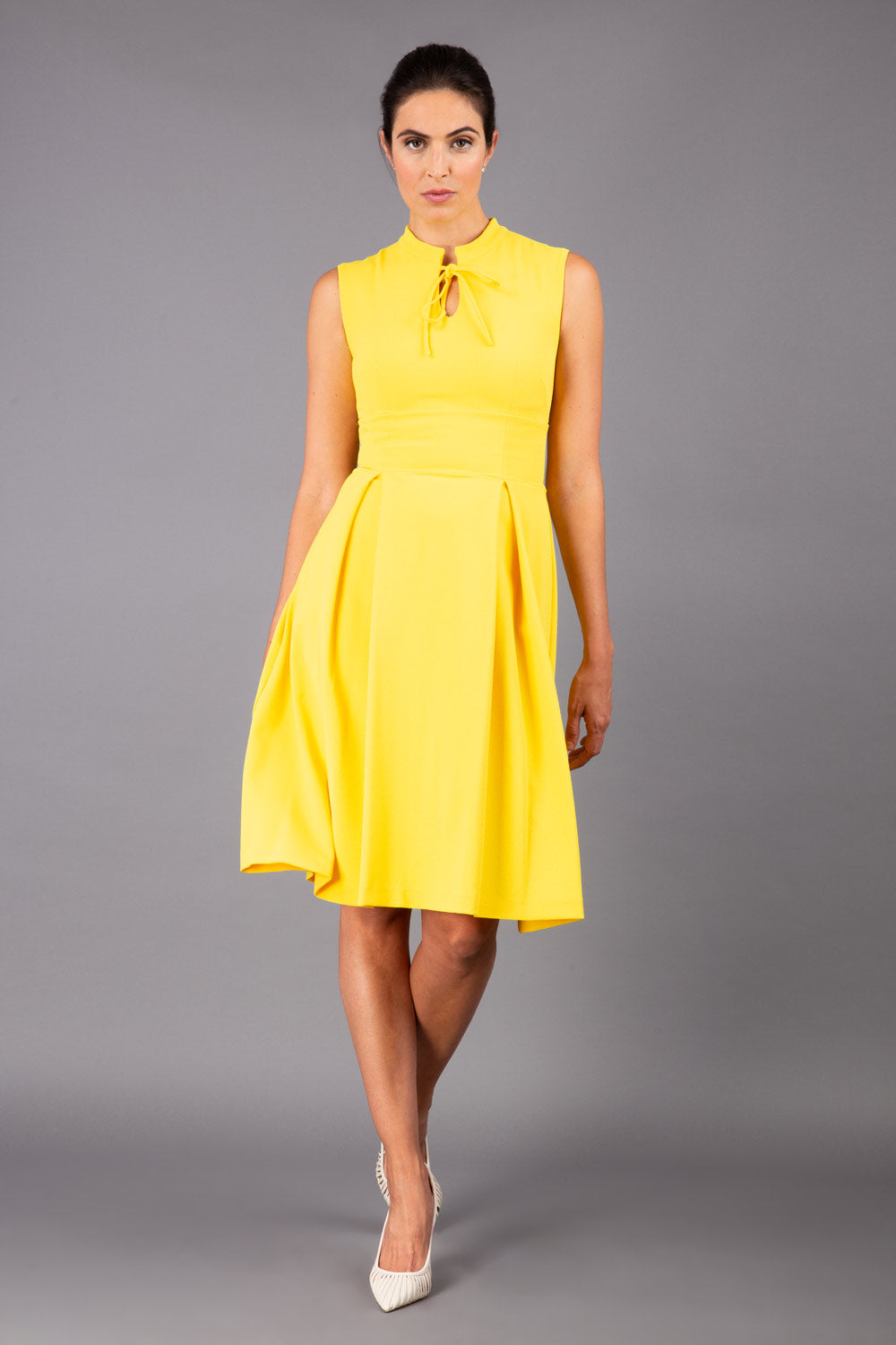 brunette model wearing diva catwalk oceana a-line swing skirt sleeveless dress with funnel neckline and tie detail in yellow front