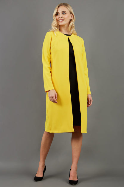 blonde model wearing the Diva Bliss Coat with round neckline in freesia yellow front image