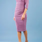 brunette model wearing diva catwalk best selling lydia pencil sleeved dress with slit at the neckline and pleating across the tummy in colour purple heart side