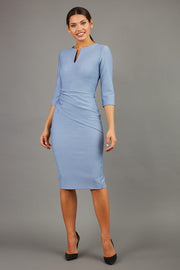 brunette model wearing seed diva catwalk milton sleeved pencil dress with a rounded neckline with a split in the middle in pale blue front