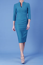 model is wearing diva catwalk seed holsworthy pencil dress with pleating on a tummy area and high neck with sleeves in pacific green front