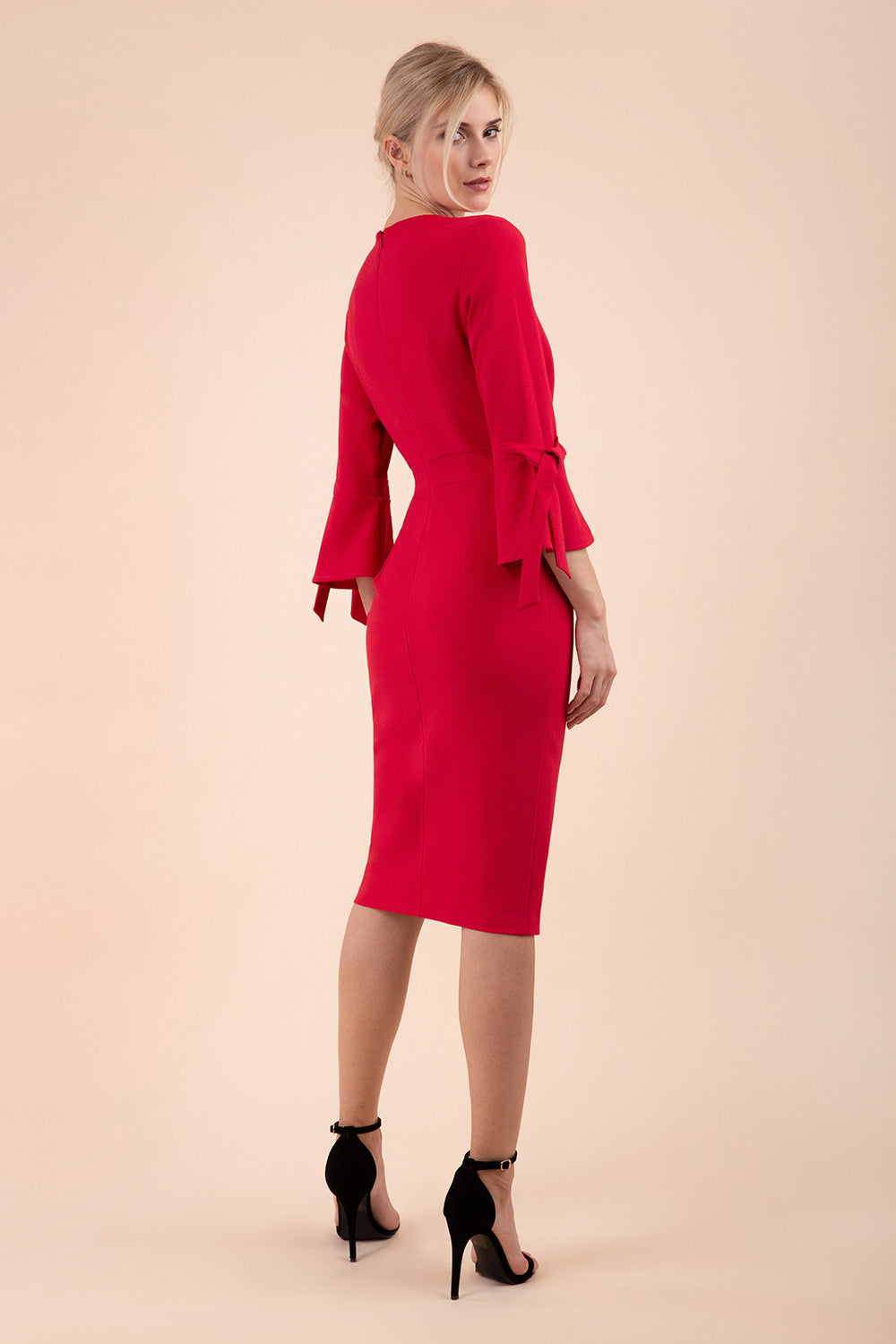 blonde model wearing diva catwalk zoe 3 4 sleeve formal dress with a split rounded neckline and split on skirt in ruby red colour back