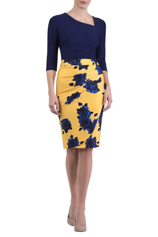 A model wearing a knee-length pencil skirt with a yellow base and blue floral print, paired with a navy top.