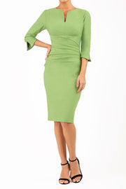 blonde model wearing seed tuscany pencil fitted dress in citrus green colour with a split in the neckline and split detail on sleeves front
