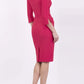 blonde model wearing seed tuscany pencil fitted dress in opera pink colour with a split in the neckline and split detail on sleeves back