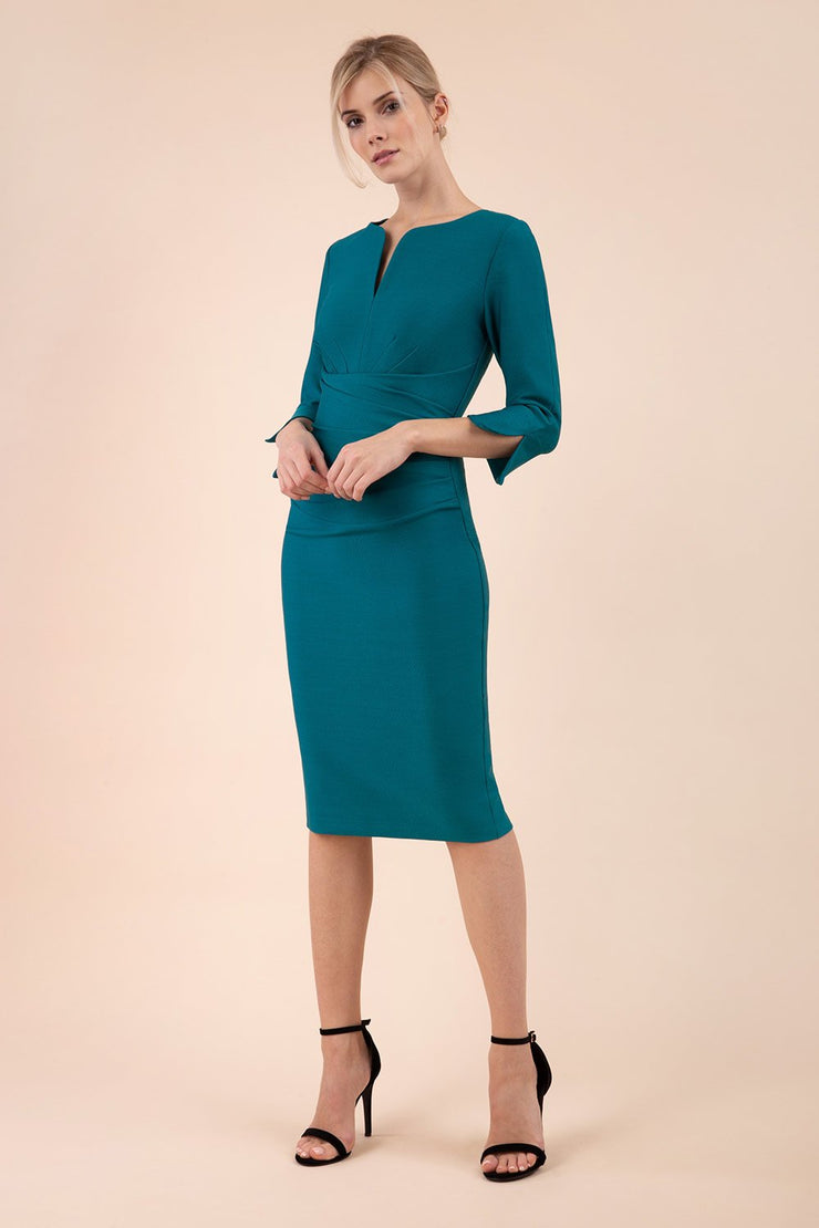 blonde model wearing seed tuscany pencil fitted dress in pacific green colour with a split in the neckline and split detail on sleeves front