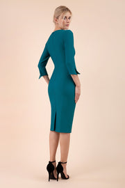 blonde model wearing seed tuscany pencil fitted dress in pacific green colour with a split in the neckline and split detail on sleeves back