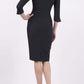 blonde model wearing seed tuscany pencil fitted dress in black colour with a split in the neckline and split detail on sleeves back