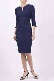 blonde model wearing seed tuscany pencil fitted dress in navy blue colour with a split in the neckline and split detail on sleeves front
